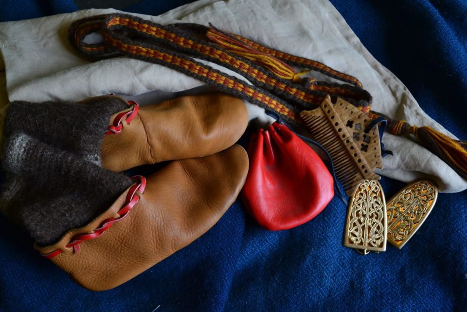 На фото ботиночки с носками, пояс, гребень, фибулы, кожаный мешочек